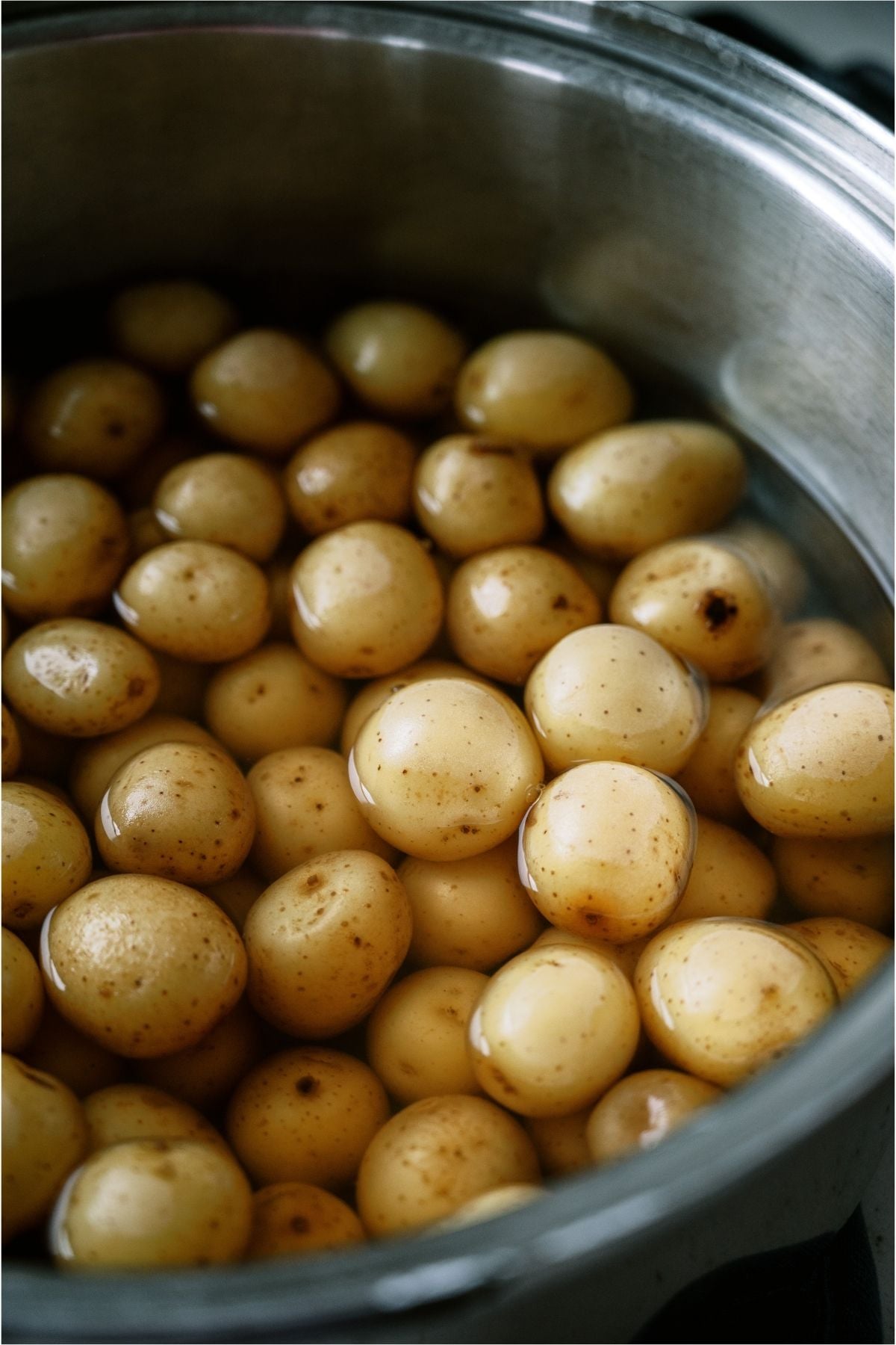 Baby potatoes in a pot with water.