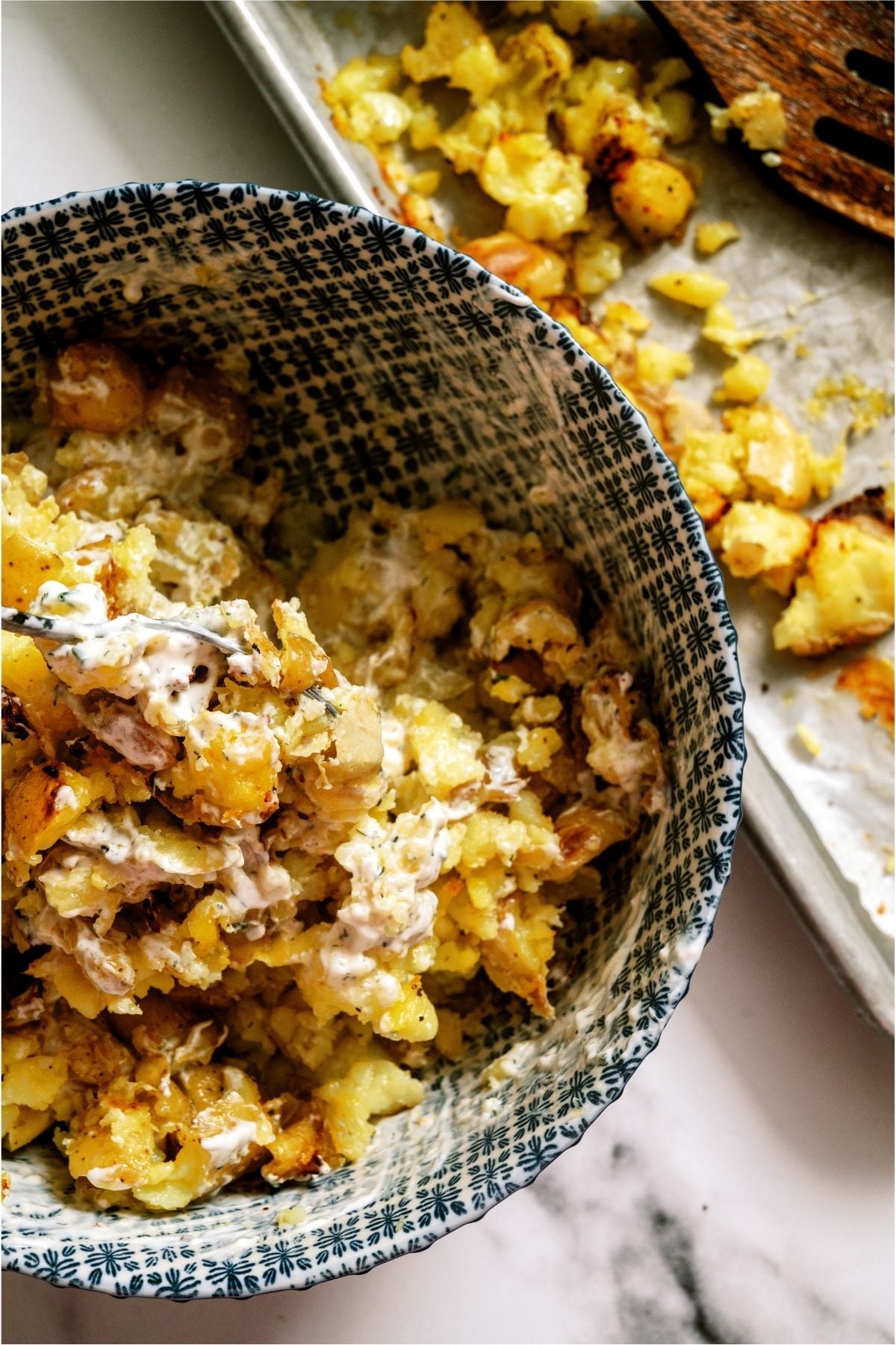 Mixing the baked potatoes in a bowl with sauce.