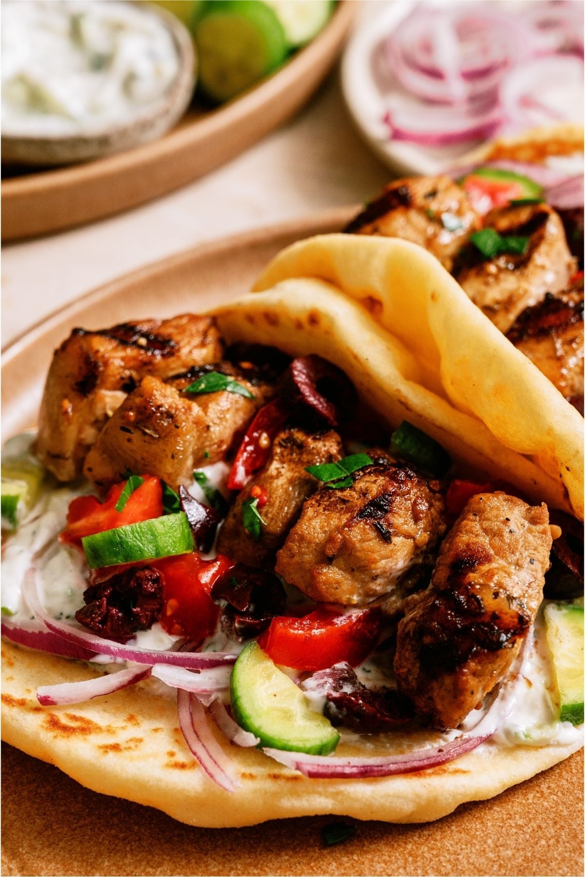Close up of Pork Souvlaki in a pita with toppings.