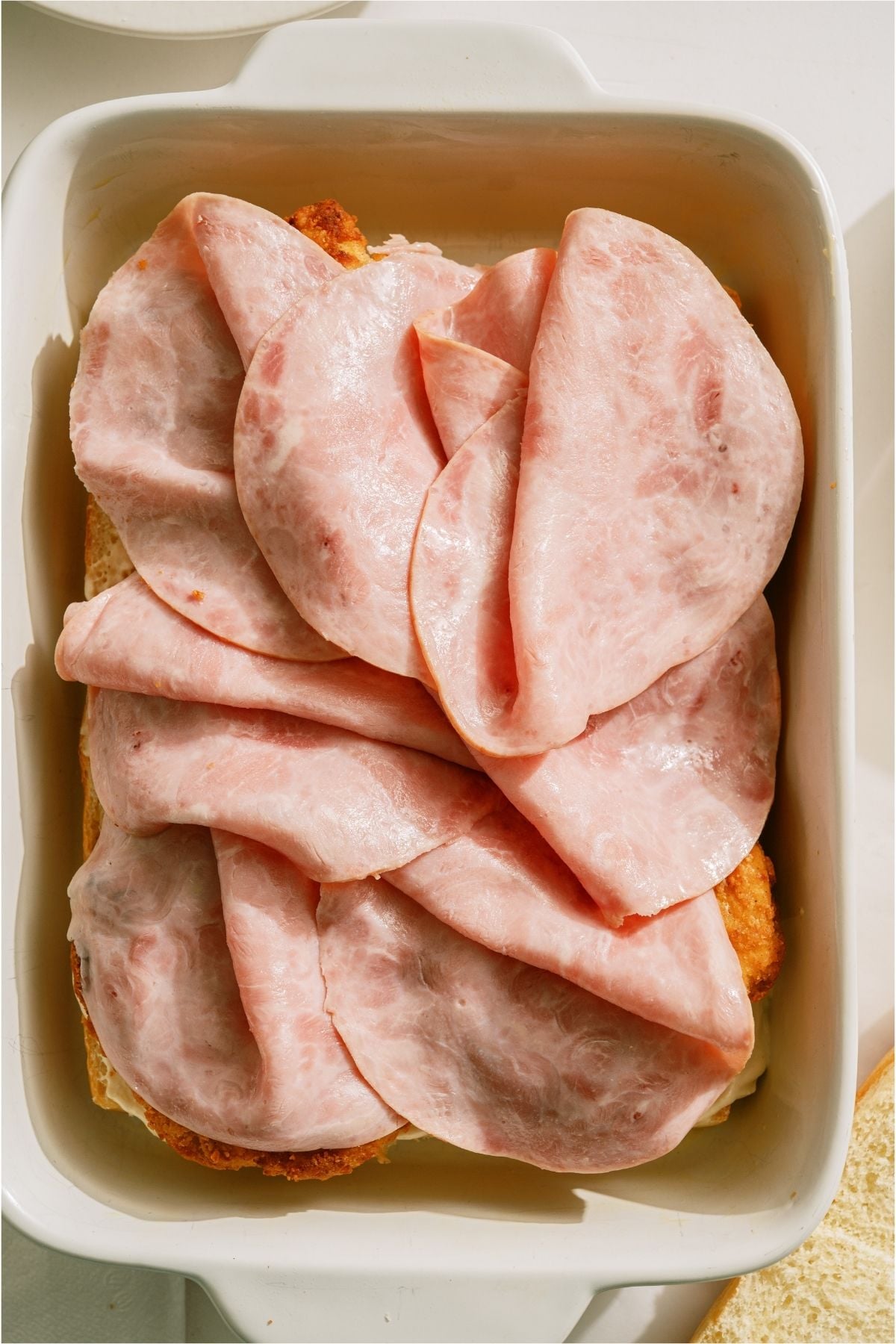 Sliced ham on top of chicken fillets.