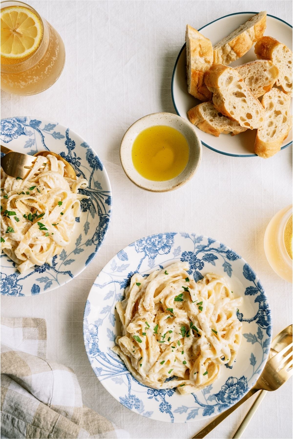 Top view of two bowls of No Fail Fettuccine Alfredo and a plate of bread.