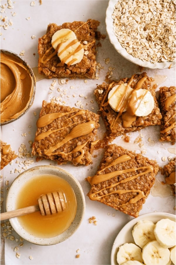 Top view of Peanut Butter Banana Oatmeal Squares wiht a bowl of honey, oats and peanut butter on the side.