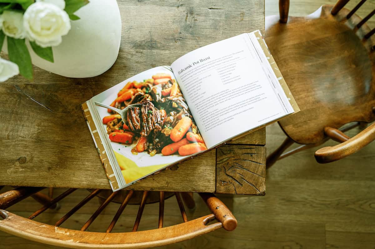 Open cookbook with a colorful recipe photo on a wooden table.