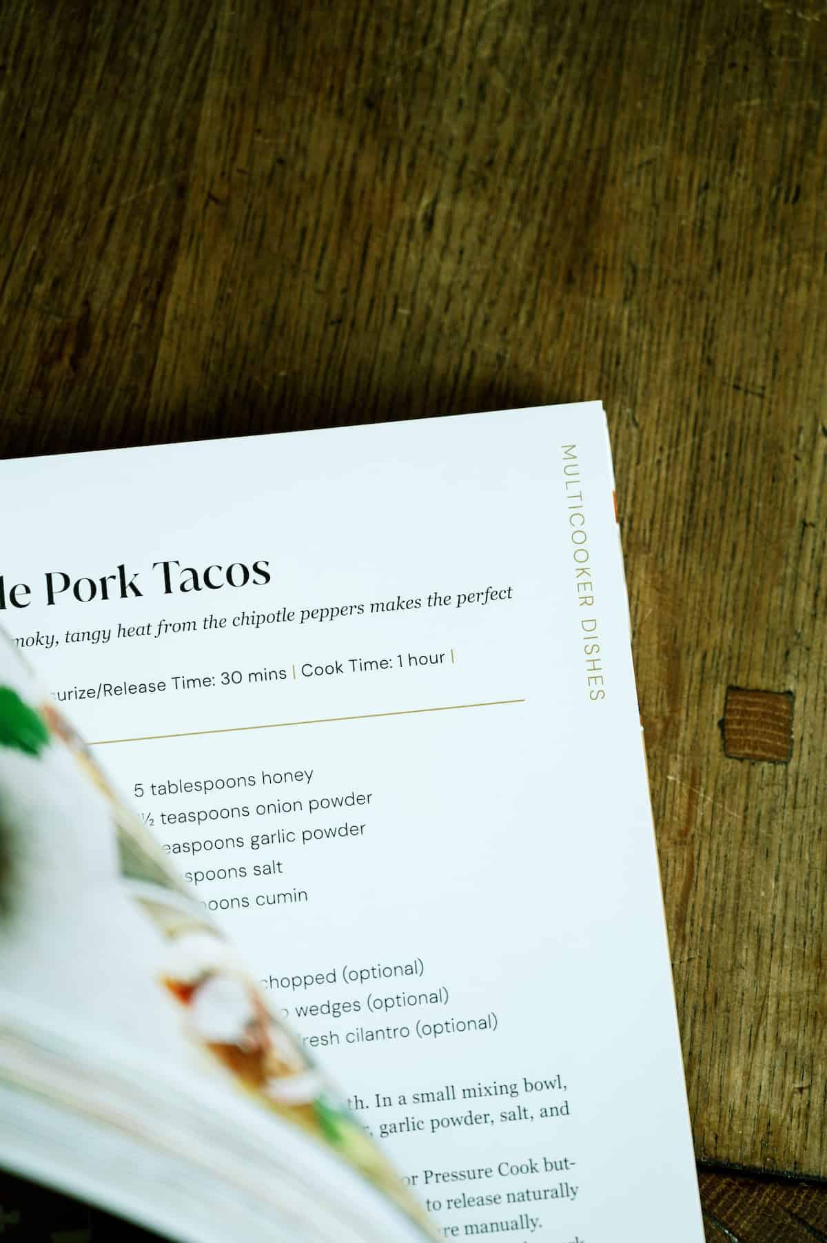 Pork tacos with fresh cilantro and onion on a wooden table.