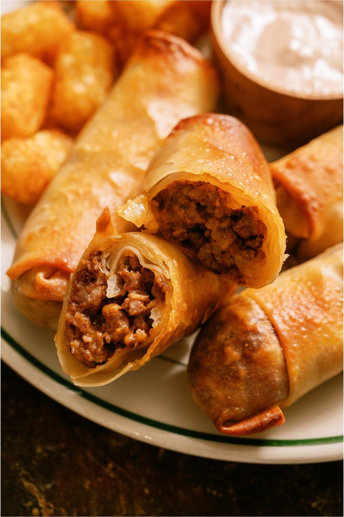 Close up of a plate of Cheeseburger Egg Rolls with 1 cut in half.