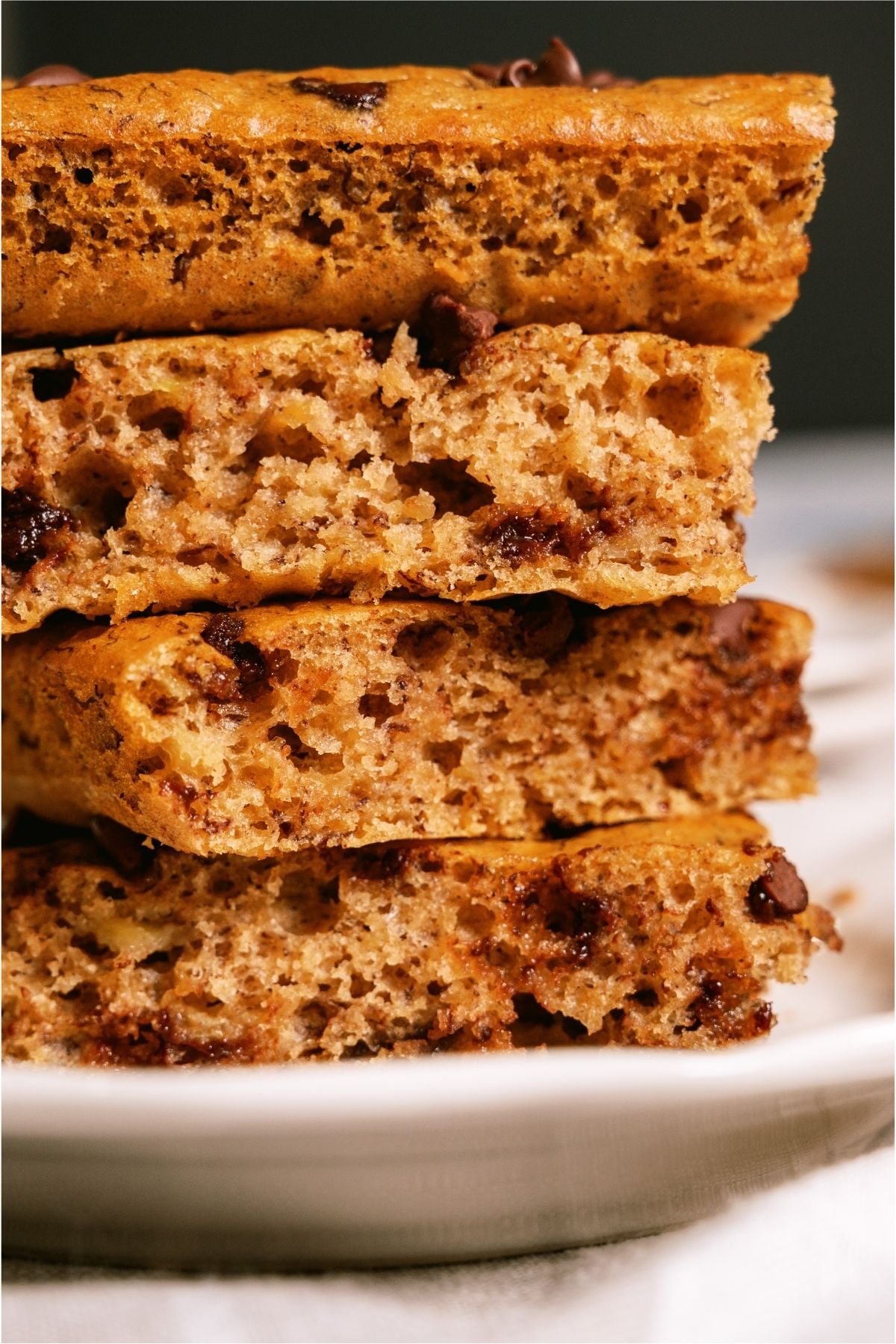 Slices of Healthier Banana Sheet Cake stacked on a plate.