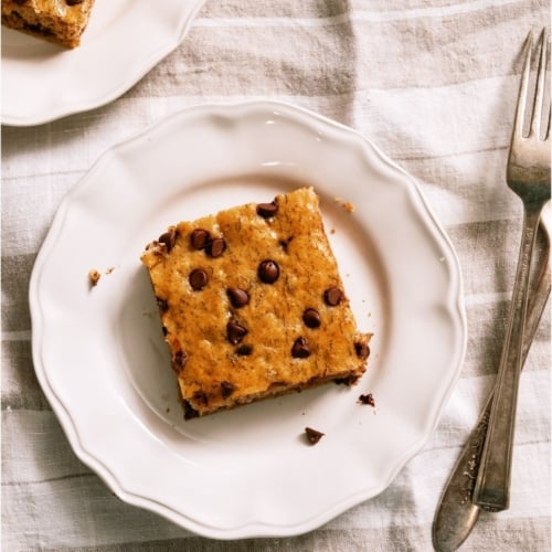 Top view of a square of Healthier Banana Sheet Cake on a white plate.