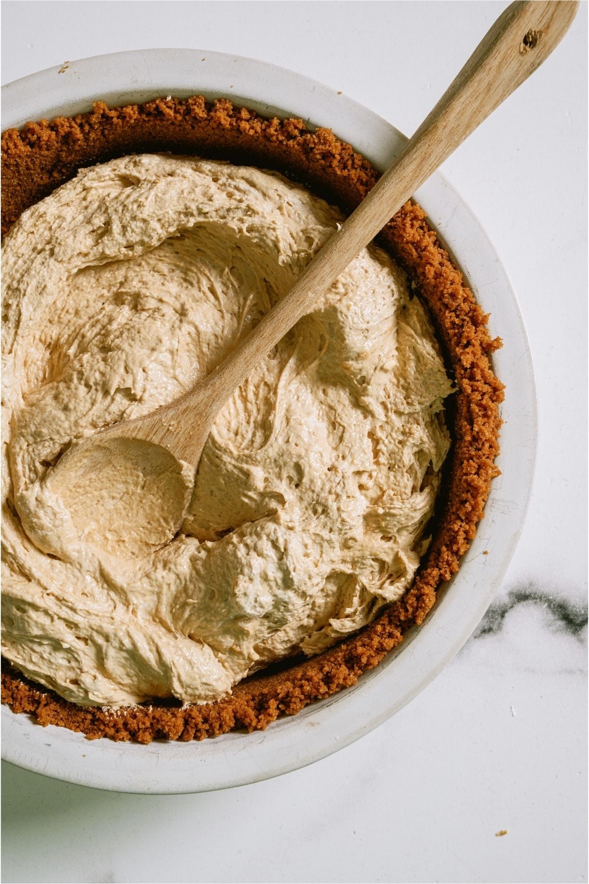 Spreading biscoff cheesecake filling into the pie crust.