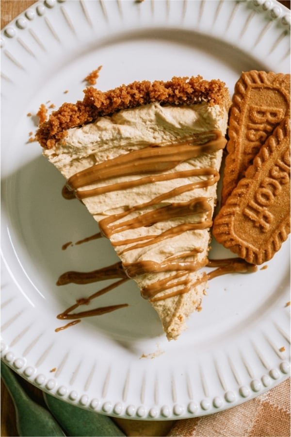 Top view of a slice of No Bake Biscoff Cheesecake on a plate with some biscoff cookies.