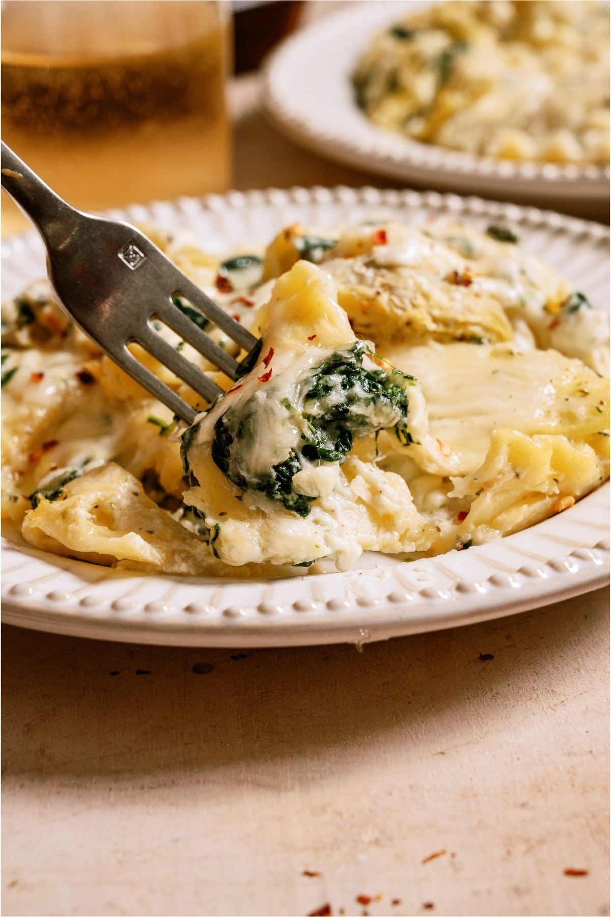 A fork lifting a bite of Sheet Pan Lasagna off a plate.