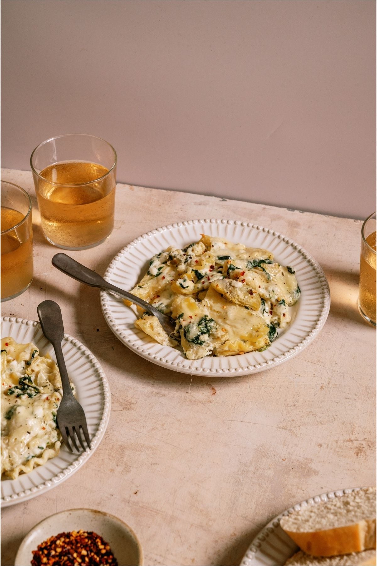 A serving of Sheet Pan Lasagna on a plate next to a drink.